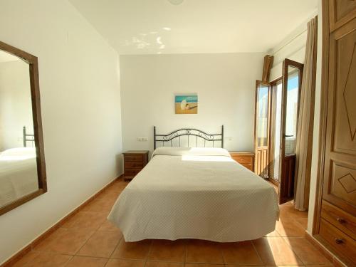 a bedroom with a white bed and a mirror at 1 linea de playa - Apartamentos - Beach & River - Conil in Conil de la Frontera