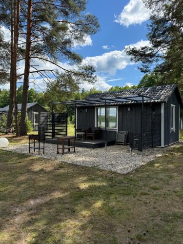 a black cabin with a bench and a swing at Pussala Latgalē in Ezerukiņi
