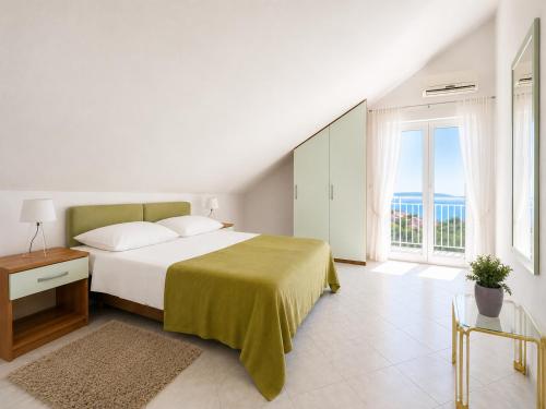 a white bedroom with a bed and a large window at Apartments Marija Magdalena in Hvar