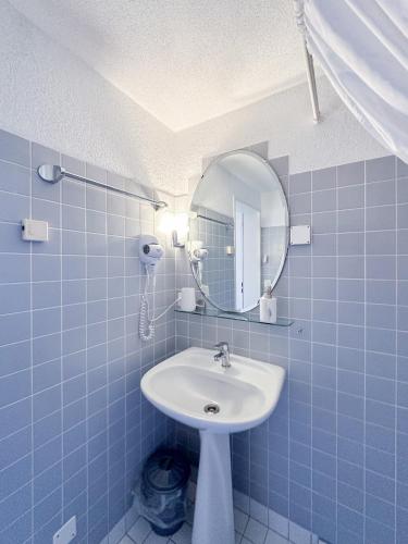 a blue tiled bathroom with a sink and a mirror at Double Room by Interlaken. Parking in Därligen