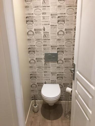 a bathroom with a toilet and a newspaper wall at Villa Des Ursulines in Bayeux