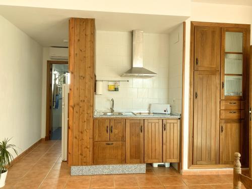a kitchen with wooden cabinets and a sink at 1 linea de playa - Apartamentos - Beach & River - Conil in Conil de la Frontera