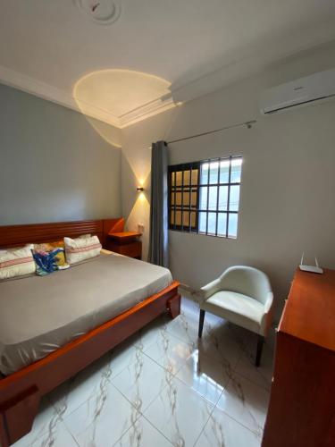 a bedroom with a bed and a chair and a window at Le cozy in Abomey-Calavi