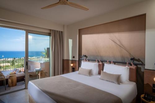 a bedroom with a large bed with a view of the ocean at Esperides Resort Crete, The Authentic Experience in Hersonissos
