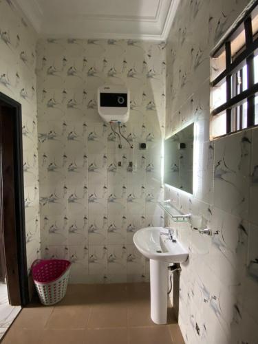 a white bathroom with a sink and a mirror at Le cozy in Abomey-Calavi
