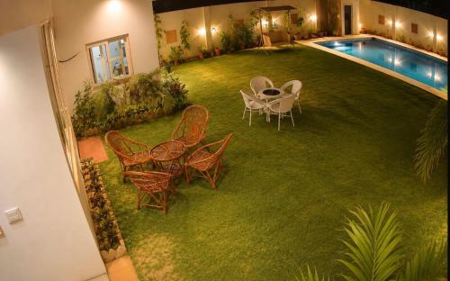 a yard with chairs and a table and a pool at Mangal Uday Villa in Jaipur