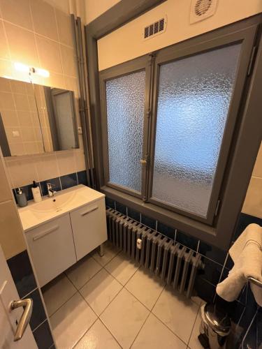a bathroom with a sink and a large window at Appartement Strasbourg Cathédrale in Strasbourg
