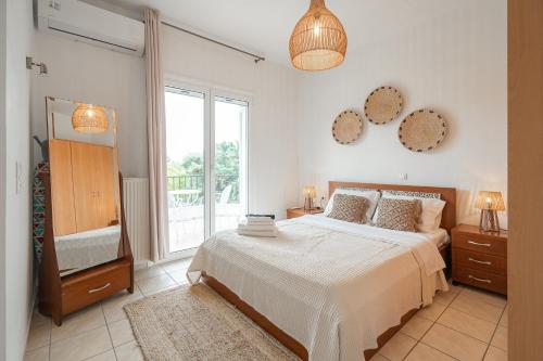 a bedroom with a bed and a tv and a window at Sunset Villa Amelia Skiathos in Skiathos National Airport