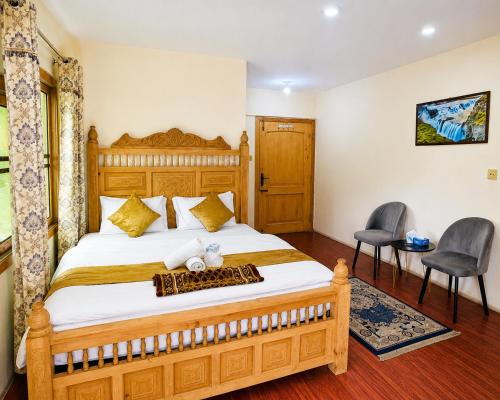 a bedroom with a large wooden bed with two chairs at IBEX COTTAGE SHARDa in Shardi