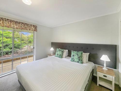 a white bedroom with a large bed and a window at Suburban Bliss - Elegant Villa 2 in Wagga Wagga
