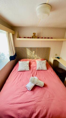 a large red bed with two towels on it at Chez Les Garçons Mobile home vintage, confortable avec piscine in Sarlat-la-Canéda