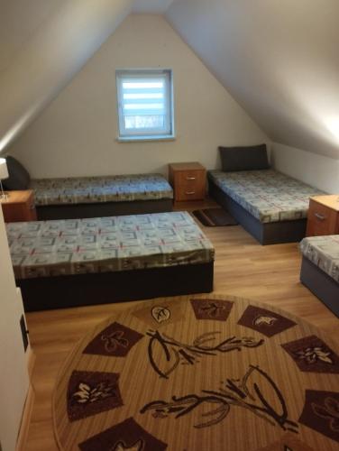 a attic room with three beds and a rug at Domki pod brzózkami in Bodzentyn