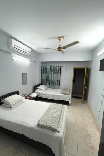 a hotel room with two beds and a ceiling fan at Rifaee Cox Palace in Cox's Bazar