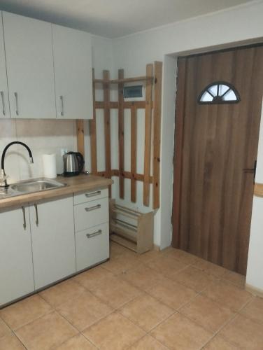 a kitchen with white cabinets and a wooden door at Domki pod brzózkami in Bodzentyn