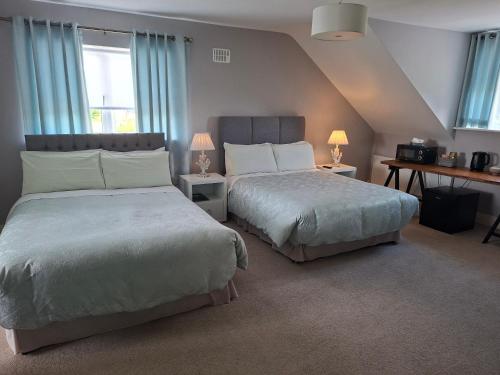 two beds in a bedroom with blue curtains and two lamps at White Quarry Hse Quarry Road in Navan