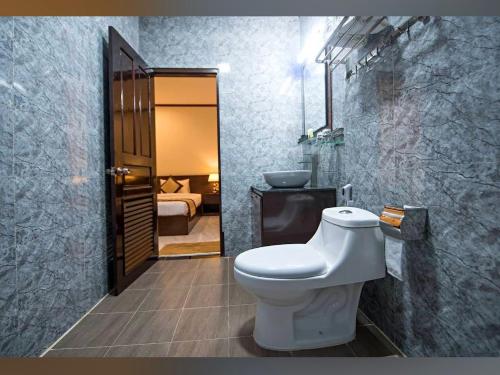 a bathroom with a white toilet and a bedroom at BON Premier Boutique Hotel in Vang Vieng