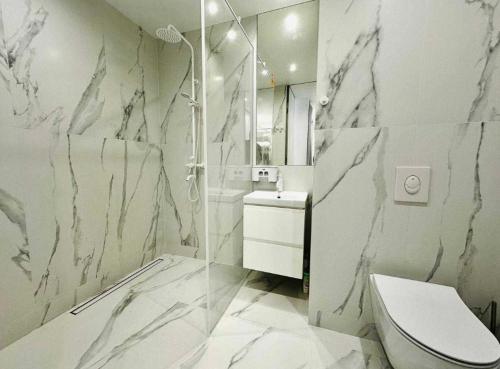 a bathroom with a marble shower and a toilet at Білі апартаменти in Dnipro
