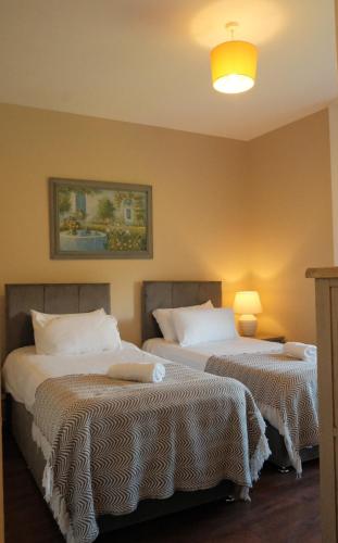 two beds in a hotel room with a light on at Flat 4, 2 Victoria Street in Armagh