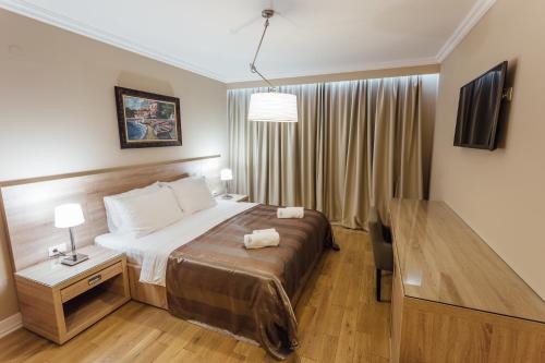a hotel room with a bed and a desk and a table at Apartments Grifone Lux in Herceg-Novi