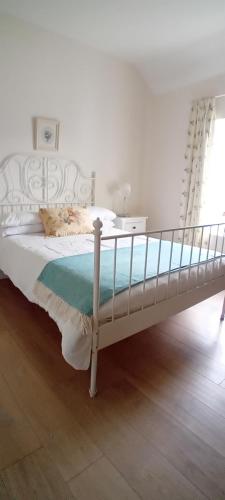 a white bed in a white room with a bed frame at Rose Cottage in Kilrean