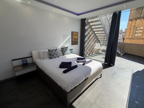 a bedroom with a bed and a large window at Cardinal Rooftop Townhouse by Aureum in Birgu