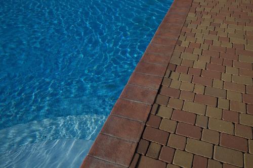 a blue swimming pool with a tiled curb next to it at Feudo Vagliasindi -Wine Experience- in Randazzo
