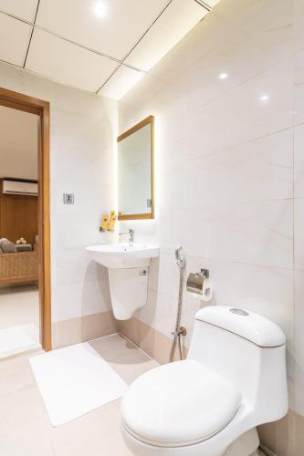 a white bathroom with a toilet and a sink at Hotel Excelsior Karachi in Karachi