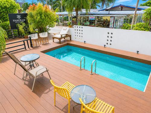 a swimming pool with chairs and a table and a table and chairs at Nangkam Boutique House in Ko Phi