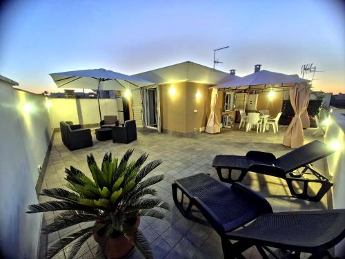 a patio with chairs and tables and umbrellas on a house at CasaKami Sky Terrace in Nettuno