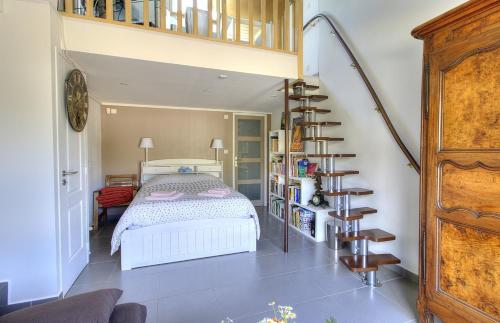 a bedroom with a bed and a spiral staircase at Chez Laurence et Thomas in Cercié