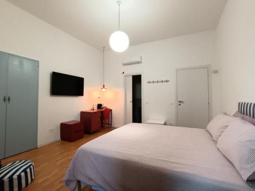 a bedroom with a white bed and a television at Studio64 in Civitavecchia