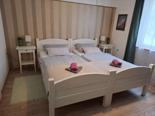 two beds in a bedroom with pink slippers on them at Rooms Bobic in Ličko Petrovo Selo
