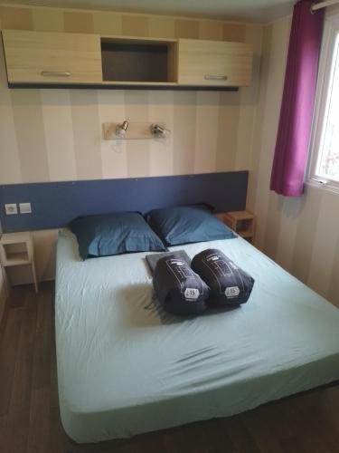 a bed in a room with two shoes on it at Camping Beausejour Sergines in Sergines