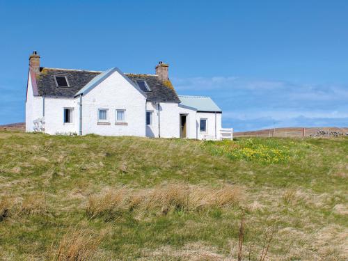a white house on top of a grassy hill at Eagle Cottage in Culkein