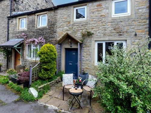 a stone house with a blue door and chairs at Rosemount Cottage in Salterforth