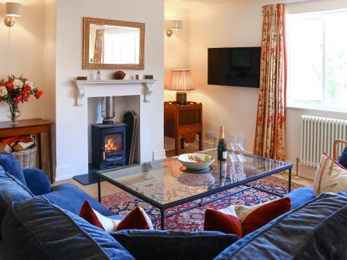 a living room with a blue couch and a fireplace at Stokewood Annexe in Freshford