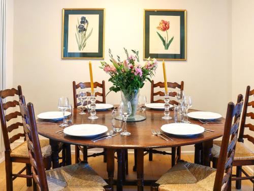 a wooden table with chairs and a vase of flowers at Stokewood Annexe in Freshford