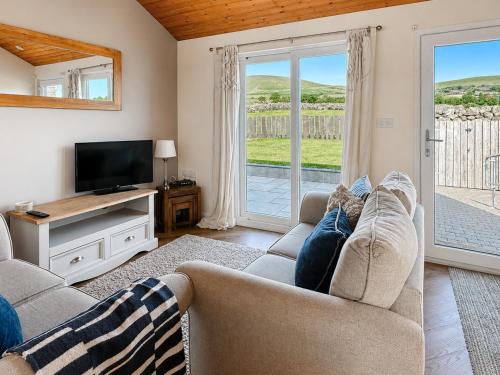 a living room with a couch and a tv at Y Gorlan - Uk6403 in Llanllechid