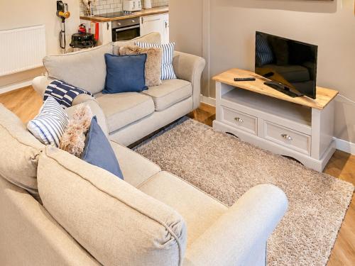 a living room with a couch and a tv at Y Gorlan - Uk6403 in Llanllechid