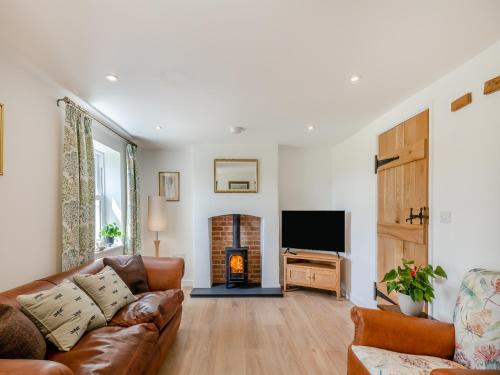 a living room with a couch and a fire place at Manor Cottage in Longham