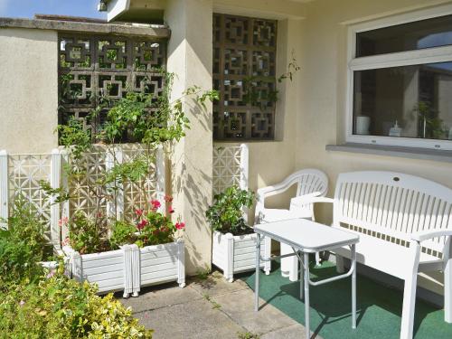 a patio with white chairs and a table and some plants at Merriview in Germoe