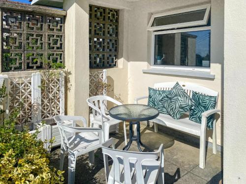 a patio with a table and chairs and a bench at Merriview in Germoe