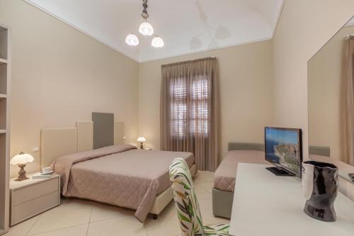 a bedroom with two beds and a flat screen tv at Ghibli Hotel in San Vito lo Capo