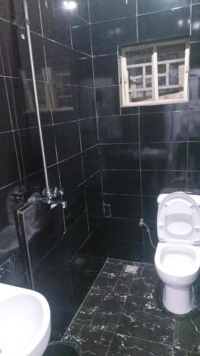 a black tiled bathroom with a toilet and a window at Lazeto Hotel & Resort in Zokoja