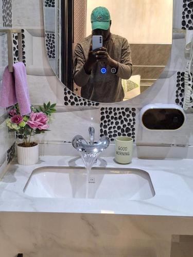 a man taking a picture of a sink in a mirror at Mamelle in Dakar