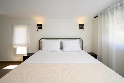 a bedroom with a large white bed with two pillows at Oropion Rental houses in Néa Palátia