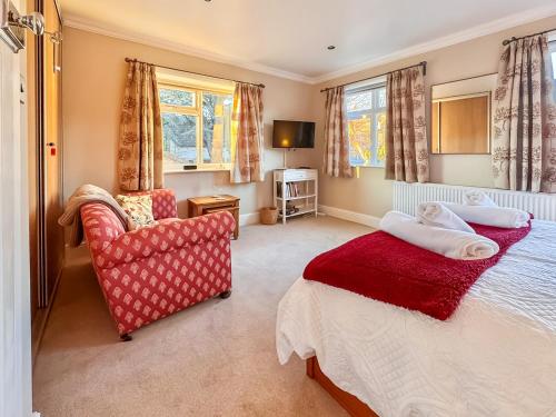 a bedroom with a bed and a chair and windows at Treetops in Baildon