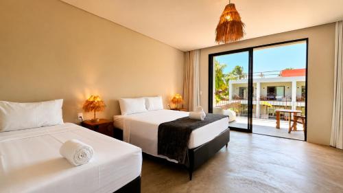 two beds in a room with a view of a patio at Luau Hotel in Flecheiras