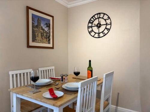 a dining room with a table with a clock on the wall at Treetops in Baildon