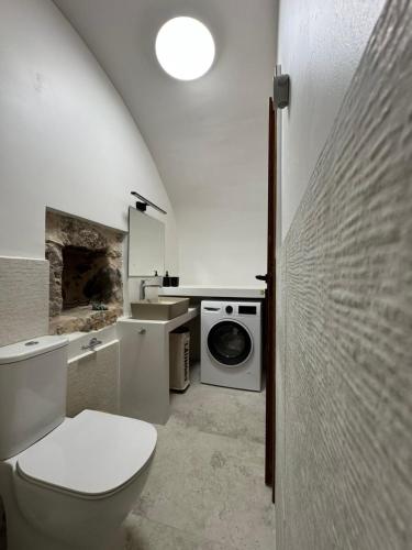 a bathroom with a toilet and a washing machine at Casa Di Lithos in Mestá